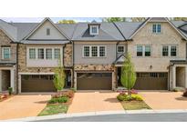 Charming townhome showcasing a two-car garage, beautiful landscaping, and stone accents at 126 Abbington River Ln, Atlanta, GA 30339