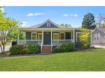 Charming home featuring a covered front porch with flowering bushes, a well-manicured lawn, and cheerful curb appeal at 873 United Se Ave, Atlanta, GA 30312