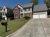 Traditional two-story home featuring brick and siding, attached two-car garage, and a well-manicured front yard at 2325 Walnut Grove Way, Suwanee, GA 30024