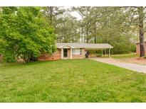 Charming brick home with a well-maintained lawn and covered carport, surrounded by mature trees at 5032 Central Church Rd, Douglasville, GA 30135