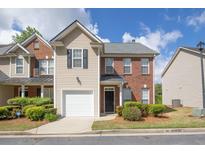 Charming townhome showcasing brick and siding exterior, attached garage, and well-maintained landscaping at 2602 Avery Park Cir, Atlanta, GA 30360