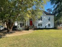 Beautiful two-story home with a lush green lawn, mature tree and a striking red front door at 1770 Bethany Spring, Cumming, GA 30041