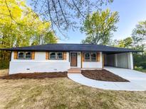 Charming renovated home with white brick, black trim, natural wood shutters, and a covered carport at 7817 Mattie Mccoy Ln, Winston, GA 30187