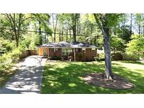 Charming brick home featuring a lush lawn, mature trees, and a long driveway at 4257 Webb Rd, Tucker, GA 30084