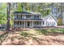 Charming two-story home features a large, covered front porch, and mature trees enhancing the landscape at 714 Lanford Springs Sw Dr, Lilburn, GA 30047