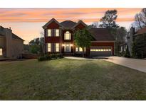 Charming brick two-story home with a well-manicured lawn and attached two car garage at sunset at 2433 Idlewood Way, Snellville, GA 30078