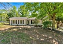 Charming single-story home with white siding, black shutters, and a well-maintained front yard with mature trees at 144 Cathy Ln, Hiram, GA 30141