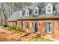 Charming brick home featuring dormer windows and black shutters, creating a classic and inviting facade at 1250 Northcliff Trce, Roswell, GA 30076