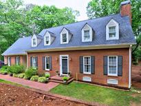 Charming brick home featuring black shutters and dormer windows, surrounded by mature trees and landscaping at 1250 Northcliff Trce, Roswell, GA 30076