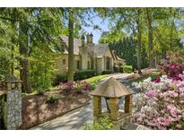 Charming stone home with lush landscaping and a private driveway nestled among mature trees at 105 Kingston Mnr, Atlanta, GA 30342