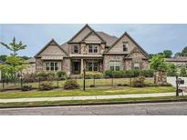 Beautiful two-story home with stone and siding, complimented by a meticulously maintained lawn and wrought iron fence at 631 Mabry Rd, Sandy Springs, GA 30328