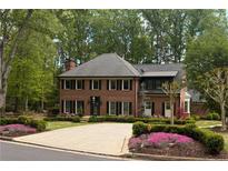 Stately brick home with manicured landscaping, mature trees, and a circular driveway at 5790 Heards Forest Dr, Atlanta, GA 30328
