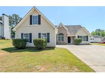 Traditional two-story home featuring vinyl siding, black shutters, mature landscaping, and a concrete driveway at 811 Betsy Ross Trl, Hampton, GA 30228