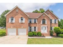 Elegant brick home featuring a two-car garage, manicured lawn, and symmetrical window shutters at 1241 Hogan Ridge Ct, Grayson, GA 30017
