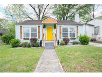 Charming home featuring a cheerful yellow door, window boxes, and a well-manicured front yard at 3078 Semmes St, East Point, GA 30344