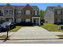 Traditional two-story townhouse featuring brick accents, tidy landscaping, and a concrete driveway at 2225 Bigwood Trl, Atlanta, GA 30349