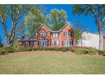 Charming two-story brick home with black shutters, a manicured lawn, mature trees, and colorful flower beds at 2566 Garrison Sw, Marietta, GA 30064