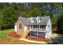 Charming two-story home with stone accents, dormers, a front porch, a lush lawn, and mature trees at 208 Wellington Walk, Douglasville, GA 30134
