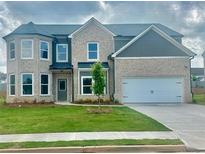 Charming two-story home featuring a brick facade, well-manicured lawn, and a two-car garage at 586 Rodeo Dr, Auburn, GA 30102