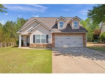 Charming home featuring a two-car garage, stone accents, dormer windows, and a well-manicured lawn at 704 Williamsburg Ct, Villa Rica, GA 30180