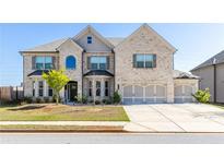 Charming two-story brick home with a three-car garage, well-manicured lawn and inviting curb appeal at 3728 In Bloom Way, Auburn, GA 30011