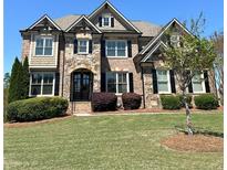 Stunning stone and brick home with manicured lawn, mature landscaping, and charming architectural details at 2671 Moon Chase Ln, Buford, GA 30519