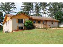 Charming ranch-style house with yellow accents, a brick facade, and a welcoming front yard with mature trees at 1584 Hebron Ln, Riverdale, GA 30296