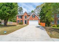 Charming two-story brick home with a well-manicured lawn and a long driveway at 3819 Meandering Sw Way, Lilburn, GA 30047