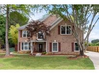 Charming two-story brick home with manicured lawn and inviting front porch with rocking chairs at 5300 Coacoochee Ter, Johns Creek, GA 30022