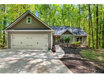 Charming home boasts well-manicured landscaping, a two-car garage, and a welcoming entrance amid a lush green backdrop at 191 Orchard Dr, Canton, GA 30115