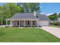 Charming home featuring a covered front porch with rocking chairs and a well-manicured lawn at 115 Braided Blanket Blf, Johns Creek, GA 30022