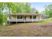 Charming single-story home with a welcoming front porch and well-maintained lawn surrounded by lush greenery at 1943 Scott Rd, Canton, GA 30115