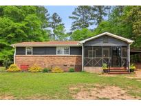 Cozy ranch style home featuring brick facade, dark siding, screened porch, and lush green front lawn at 160 Oglesby Bridge Rd, Conyers, GA 30094