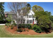 Charming two-story home with a manicured lawn, lush landscaping, and a welcoming red front door at 1485 Mill Place Dr, Dacula, GA 30019
