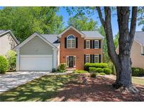 Charming two-story brick home featuring black shutters, lush landscaping, and a well-manicured lawn at 160 Brookhollow Trce, Alpharetta, GA 30022