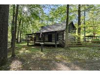 Charming log cabin with a covered front porch nestled among mature trees at 3401 Clay Rd, Austell, GA 30106