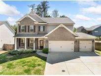 Charming two-story home featuring a brick and siding exterior, attached three-car garage, and well-manicured lawn at 3875 Grandview Manor Dr, Cumming, GA 30028
