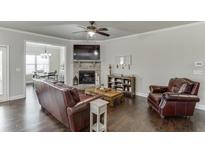 Cozy living room features a stone fireplace, ceiling fan, and hardwood floors at 110 Legion Dr, Buford, GA 30518