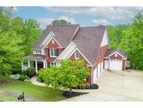 Beautiful brick home with a well-manicured lawn and a three-car garage surrounded by lush trees at 51 Sagemont Ct, Acworth, GA 30101