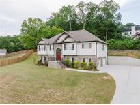 Charming two-story home features a stone facade, brick accents, well-manicured lawn, and a long driveway at 204 Arapahoe Ct, Villa Rica, GA 30180