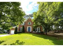 Charming two-story brick home with a well-manicured lawn, mature trees, and a welcoming blue front door at 4213 Schooner Ne Ct, Roswell, GA 30075