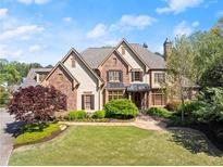 Stunning two-story brick home featuring a manicured lawn, lush landscaping, and a welcoming front entrance at 3562 Langley Oaks Se Ct, Marietta, GA 30067