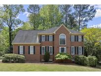 Charming two-story brick home featuring a manicured lawn, lush landscaping, and dark green shutters at 2130 Federal Rd, Roswell, GA 30075