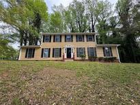 Traditional two-story home with tan siding, black shutters, and mature trees in a large front yard at 5183 Mccarter Ct, Stone Mountain, GA 30088