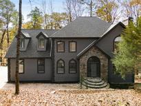 Charming two-story gray home featuring a stone archway entrance and classic architectural details nestled among the trees at 270 Boulder Dr, Roswell, GA 30075