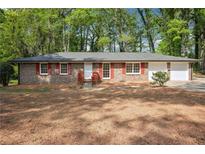 Charming single story brick home with red shutters and an attached two car garage at 5935 Christopher Ln, Lithonia, GA 30058