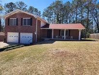 Charming brick home with a two-car garage and a cozy front porch nestled among mature trees in the yard at 2117 Chestnut Hill Cir, Decatur, GA 30032