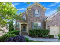 Charming brick home with a well-manicured lawn, complemented by lush landscaping and a welcoming entrance at 213 Roseman Way, Woodstock, GA 30188