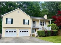 Charming two-story home with a two-car garage, front porch, landscaped yard, and mature trees at 1043 Foxhollow Trl, Canton, GA 30115