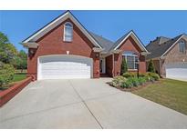 Charming brick home with a two-car garage, manicured landscaping, and a well-maintained lawn at 1610 Glenhurst Dr, Snellville, GA 30078